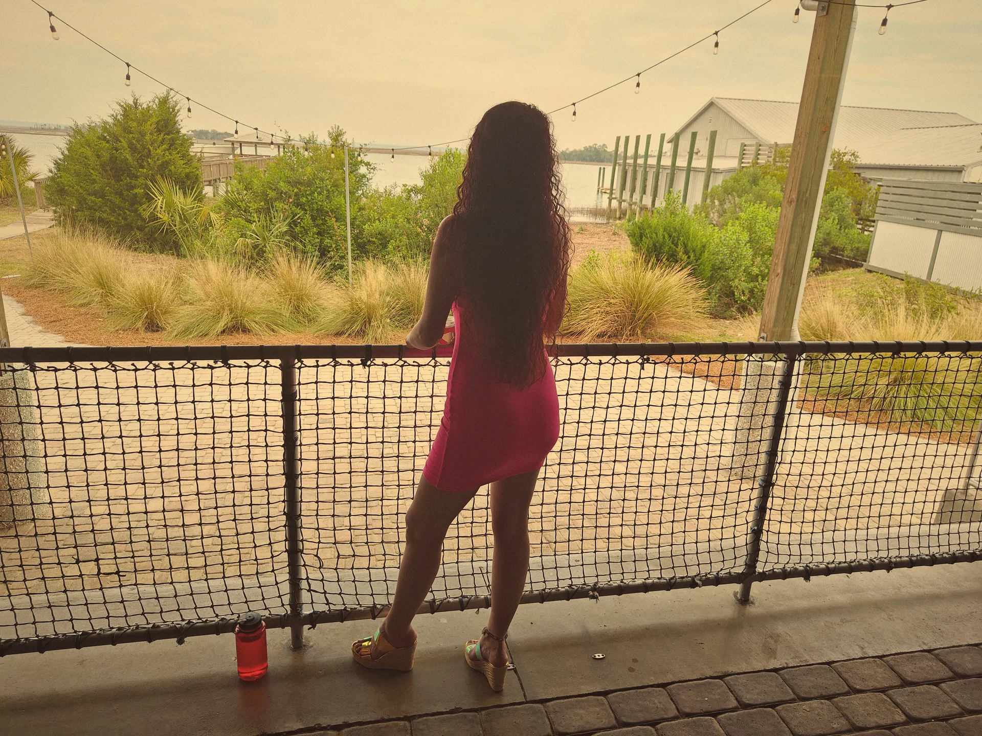 Alice Seal in a pink dress at golden hour, looking out over a Lowcountry marina from a covered dock